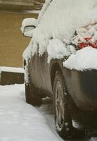 fragment de la voiture sous une couche de neige après une forte chute de neige. le corps de la voiture est recouvert de neige blanche photo
