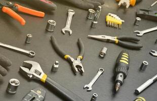 trousse à outils de bricoleur sur une table en bois noire. de nombreuses clés et tournevis, piles et autres outils pour tous types de travaux de réparation ou de construction. outils de réparateur photo