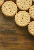 un biscuit sandwich rond fourré à la noix de coco se trouve en grande quantité sur une surface en bois marron. photo de friandises comestibles sur un fond en bois avec espace de copie