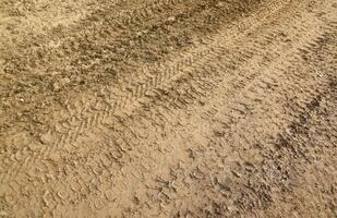 roue Piste sur boue. traces de une tracteur ou lourd hors route voiture sur marron boue dans humide Prairie photo