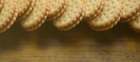 un biscuit sandwich rond fourré à la noix de coco se trouve en grande quantité sur une surface en bois marron. photo de friandises comestibles sur un fond en bois avec espace de copie