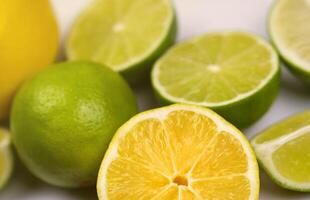 de nombreuses moitiés et tranches de citron jaune et de citron vert sur une table blanche claire. fruits frais sur le dessus en bois de la cuisine photo