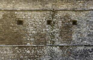 très vieux brique pierre mur de Château ou forteresse de 18e siècle. plein Cadre mur avec obsolète sale et fissuré briques photo