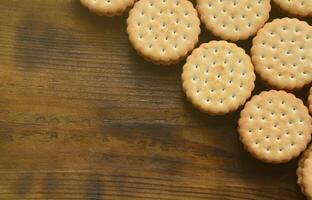 un biscuit sandwich rond fourré à la noix de coco se trouve en grande quantité sur une surface en bois marron. photo de friandises comestibles sur un fond en bois avec espace de copie