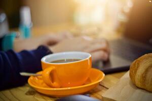 femmes en utilisant portable travail et nettoyer mains avec de l'alcool boisson café tasse chaud à Accueil photo