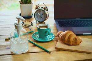 femmes en utilisant portable travail et nettoyer mains avec de l'alcool boisson café tasse chaud à Accueil photo