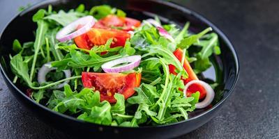 salade de légumes frais roquette, tomate, assiette d'oignon collation repas sur la table copie espace fond de nourriture