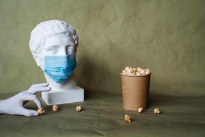 le concept de alimentation une la personne dans une médical masque avec nourriture, effusion nourriture dans de face de le visage dans une masque, verser pop corn de une pot sur le tableau, plâtre tête dans une protecteur masque, quarantaine, art photo