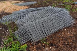 le fer la grille avec carré cellules pour le construction travaux, une métal grille plié dans une pile photo