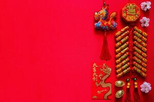 pétards pour chinois Nouveau année mot signifier richesse, bénédiction avec or lingots mot signifier richesse, rouge enveloppe paquet mot signifier bien la chance et bien fortune et pendentif dragon sur rouge Contexte. photo