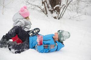 une fille et une garçon dans une neigeux forêt sont équitation un la glace faire glisser vers le bas une glisser. photo de une enfant dans une hiver forêt. hiver, hiver vacances, les vacances, les vacances.