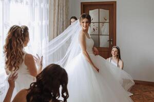 copains réjouir avec le la mariée dans le Matin. elles ou ils prendre des photos, sourire, Aidez-moi le la mariée boucler sa robe. photo