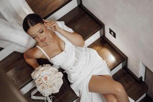 magnifique mariée, à la mode portrait dans une élégant intérieur. brunette mariée, content femme portant mariage blanc robe avec mariage maquillage et coiffure. Haut photo de le la mariée. jeunes mariés