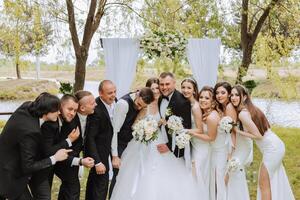 toute la longueur portrait de le jeunes mariés et leur copains à le mariage. le la mariée et jeune marié avec demoiselles d'honneur et copains de le jeune marié sont ayant amusement et réjouissance à le mariage. photo