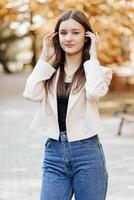 verticale photo. magnifique insouciant Jeune adolescent fille dans décontractée vêtements. portrait de une magnifique fille contre le Contexte de la nature avec une flou Contexte. photo