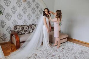 copains réjouir avec le la mariée dans le Matin. elles ou ils prendre des photos, sourire, Aidez-moi le la mariée boucler sa robe. photo