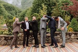 joyeux, jeune, énergique les témoins de le jeune marié suivant à le jeune marié. copains féliciter le jeune marié. jeune marié et le sien marrant copains ayant amusement sur le mariage journée de le jeunes mariés. photo