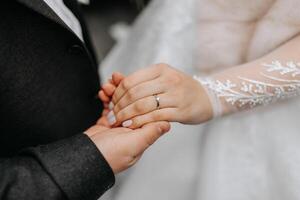 le jeune marié tendrement détient le de la mariée main après placement une mariage bague sur sa doigt à une mariage cérémonie. une magnifique mariage dans le du froid saison. photo