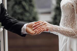 le homme doucement détient le de la mariée main avec une magnifique d'or mariage anneau. agrandi image de jeunes mariés' mains. mariage concept. le jeune marié doucement touche le la mariée photo