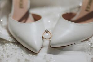 détails de le la mariée. beauté est dans le détails. talon haut de mariée chaussures. or mariage bague avec une diamant. parfums. des boucles d'oreilles mariage dans détails. photo