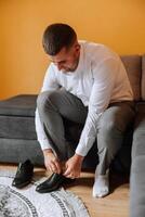 une homme mains attacher le lacets de le sien Nouveau chaussures. personnes, entreprise, mode et chaussure concept - fermer de une homme jambes et mains attacher les lacets. le jeune marié met sur le sien chaussures. photo