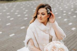 portrait de une magnifique la mariée avec une mariage bouquet de fleurs, attrayant femme dans une mariage robe avec une longue voile. content la mariée femme. la mariée avec mariage maquillage et coiffure. hiver mariage photo