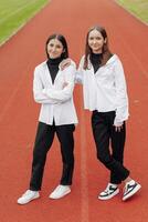 portrait de deux adolescent les filles dans décontractée vêtements séance dans une stade et posant à la recherche à le caméra. concept de amitié. une moment de Bonheur. photo