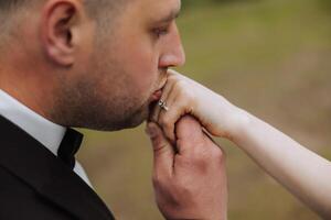 le jeune marié baisers le main de le la mariée. tondu photo. dans essentiel détails. tendresse photo