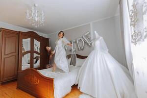 des ballons la mariée et une magnifique la mariée séance sur une lit dans une luxueux boudoir robe en train de préparer pour le mariage cérémonie. photo