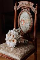 Accueil style. mariage bouquet de crème et rose fleurs sur une chaise à Accueil en dessous de lumière du jour. détails de le la mariée et jeune marié. photo