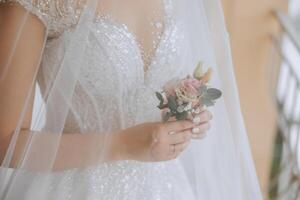 mariage boutonnière de fleurs dans le mains de le la mariée. mariage détails. le premier réunion de le la mariée et jeune marié. le la mariée est attendre pour le jeune marié. photo