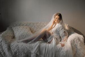 agréable mignonne fille dans une boudoir peignoir. content magnifique la mariée en dessous de voile. mode, beauté, style. Matin de le la mariée. magnifique la mariée avec élégant faire en haut et cheveux style. photo