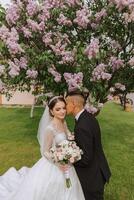 mariage. l'amour et couple dans jardin pour mariage. célébrer le la cérémonie et engagement. enregistrer le date. confiance. le la mariée et jeune marié embrasse contre le Contexte de une printemps épanouissement arbre. photo