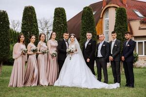 toute la longueur portrait de le jeunes mariés et leur copains à le mariage. le la mariée et jeune marié avec demoiselles d'honneur et copains de le jeune marié sont ayant amusement et réjouissance à le mariage. photo