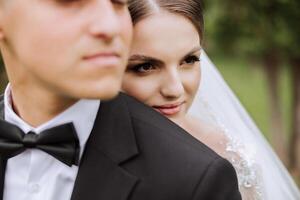 mariage. l'amour et couple dans jardin pour mariage. fête de la cérémonie et engagement. enregistrer le date. confiance. le la mariée et jeune marié embrasser. sourire et l'amour. le la mariée câlins le jeune marié par le épaules. photo