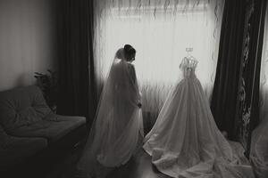 une content la mariée est en train de préparer pour sa luxueux mariage dans une Hôtel chambre, avec une mariage robe sur une mannequin proche. portrait de une femme avec à la mode cheveux, maquillage et une sourire dans une pansement robe. photo