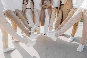 amitié, mouvement, action, liberté et gens concept - groupe de content adolescents ou école copains posant et ayant amusement en plein air. tondu photo de gens qui élevé leur jambes.