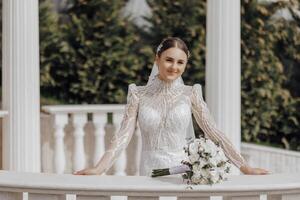 le la mariée dans une longue robe des stands près blanc Colonnes dans le romain style. magnifique cheveux et se maquiller. un exquis mariage photo