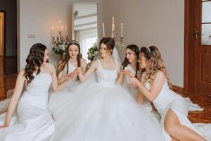 copains réjouir avec le la mariée dans le Matin. elles ou ils prendre des photos, sourire, Aidez-moi le la mariée boucler sa robe. photo