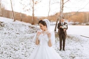 mariage portrait de le la mariée et jeune marié. hiver marcher dans la nature. le la mariée des stands dans de face de le jeune marié. photo