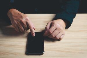 Haut vue de homme d'affaire dans costume asseoir sur table en portant et toucher téléphone intelligent. photo