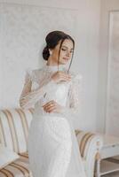 mode portrait de une magnifique la mariée dans une luxueux mariage robe avec dentelle et cristaux dans un arabe intérieur style. brunette content femme portant mariage robe avec mariage maquillage et coiffure. photo