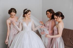 copains réjouir avec le la mariée dans le Matin. elles ou ils prendre des photos, sourire, Aidez-moi le la mariée boucler sa robe. photo