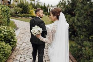 une marcher de magnifique les mariées sur leur mariage journée dans une magnifique emplacement. contre le Contexte de une moderne maison. photo de le retour