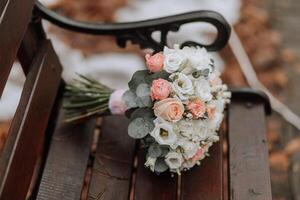 le de la mariée bouquet sur une marron banc. hiver mariage. une marcher dans le forêt photo