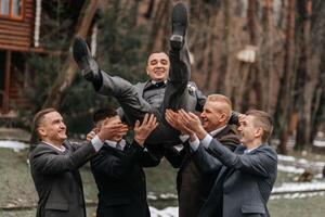 le jeune marié et le sien copains sont habillé dans combinaisons, tromper autour dans la nature pendant une photo tirer. une groupe de Hommes. mariage dans la nature