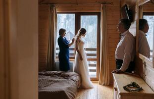 photo avec Parents à le mariage. content Parents Aidez-moi et réjouir pour leur bientôt marié fille. émouvant des moments à le mariage. mère cravates le robe de sa fille la mariée