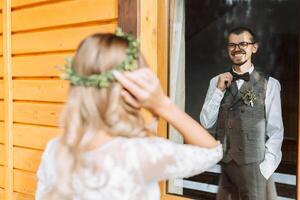 le premier réunion de le la mariée et jeune marié. il regards à son. Beau et souriant Jeune jeune marié. mariage dans une rustique style photo