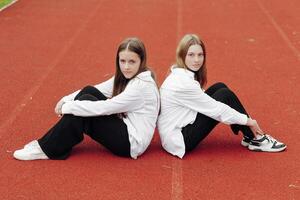 portrait de deux adolescent les filles dans décontractée vêtements séance dans une stade et posant à la recherche à le caméra. concept de amitié. une moment de Bonheur. photo