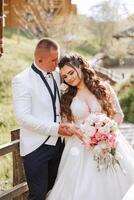 mariage. l'amour et couple dans jardin pour mariage. fête de la cérémonie et engagement. enregistrer le date. confiance. le la mariée et jeune marié embrasser. sourire et l'amour dans le parc. le jeune marié embrasse le la mariée. photo